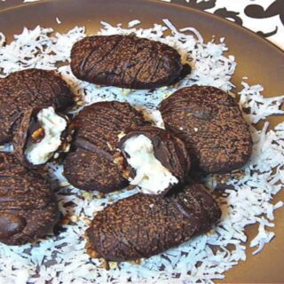 A round brown plate filled with homemade almond joy candy on a bed of white coconut
