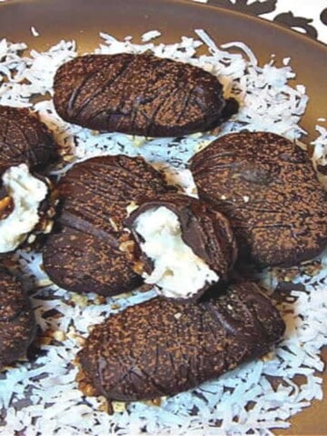 A round brown plate filled with homemade almond joy candy on a bed of white coconut