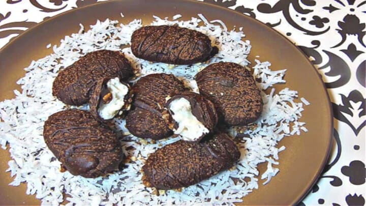 A round brown plate filled with homemade almond joy candy on a bed of white coconut
