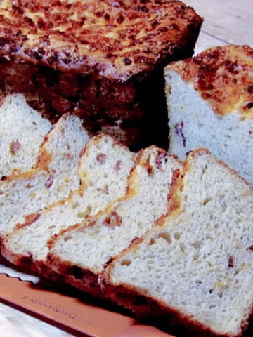 A sliced loaf of Bacon Cheddar Scallion Bread along with a serrated knife in the foreground.