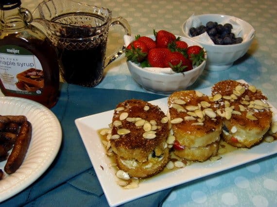 Three servings of Stuffed Red, White, and Blue French Toast on a white plate with slivered almonds on top.