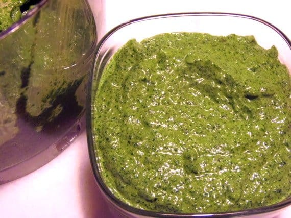 A closeup of a glass bowl filled with Cilantro Pesto.