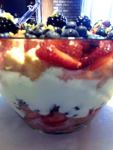 A Rec, White, and Blueberry Trifle in a glass dish with vanilla pudding.