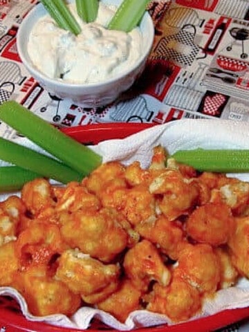 A basket filled with Buffalo Cauliflower with celery sticks and blue cheese dressing.