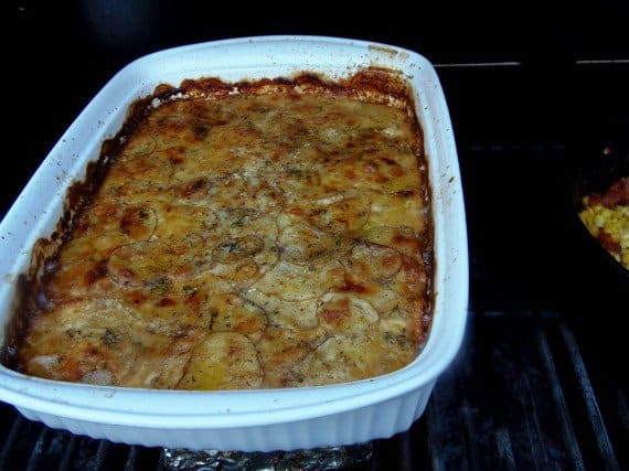 A white rectangle baking dish filled with brown and cheese Potato Gratin with Beer Cheese Sauce.