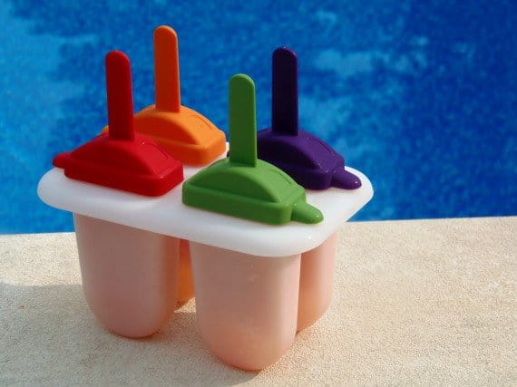 Trop-Pops Popsicles Tropical Popsicle Recipe in popsicle holders with multi-colored tops.