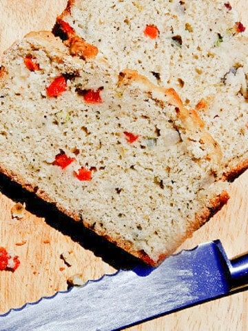 Two slices of Veggie Beer Bread on a wooden board with a serrated knife.