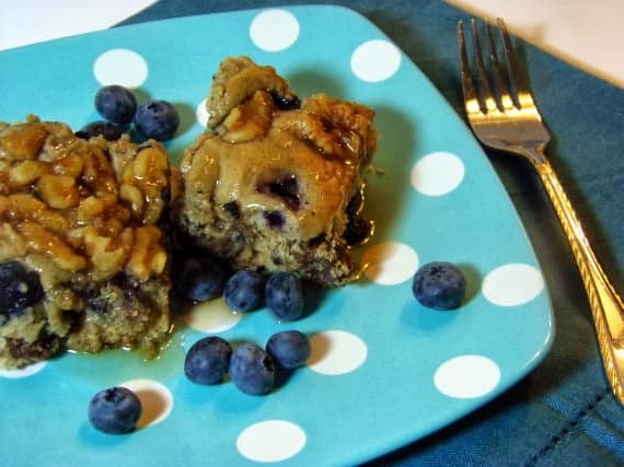 Two slices of sausage blueberry breakfast casserole on a blue and white polka dot plate with fresh blueberries