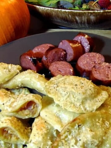 A bunch of Pumpkin Potato Pierogies along with sausage on a plate