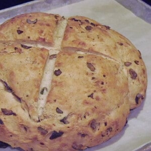 A round loaf of Rustic Olive Bread on a baking sheet.