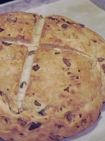 A round loaf of Rustic Olive Bread on a baking sheet.