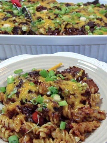 A plate of Cincinnati Chili in the foreground and a casserole dish in the background.