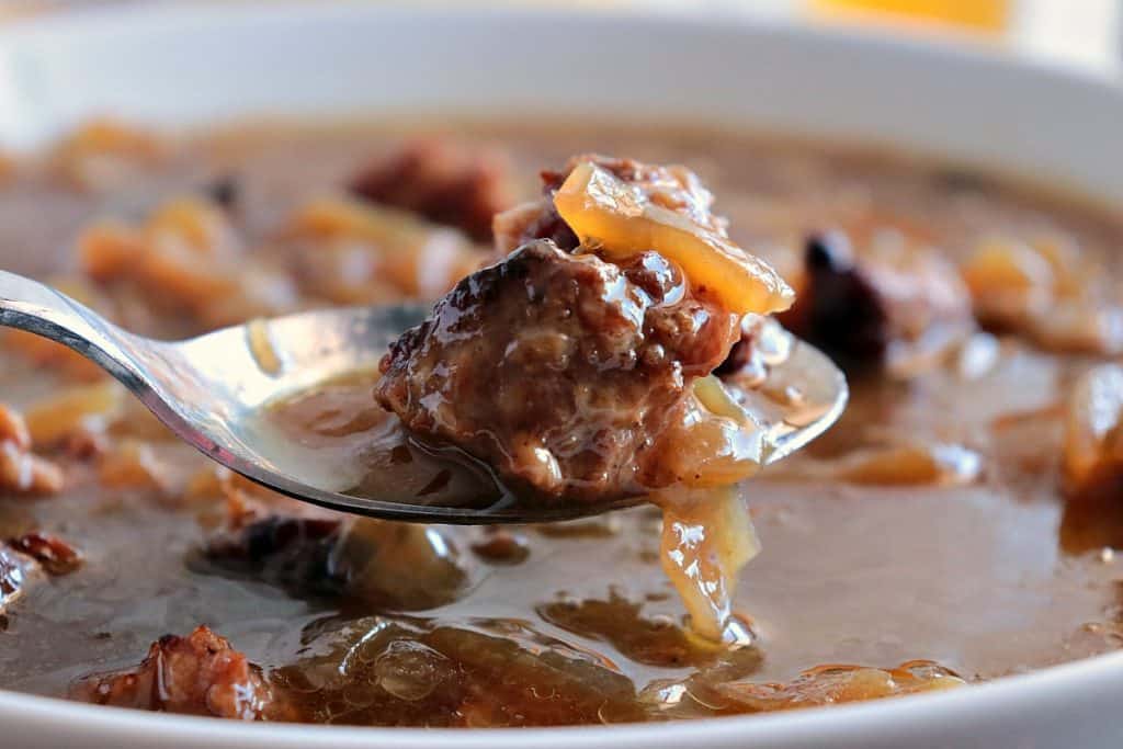 Closeup of a spoonful of German Soup with German Sausage and onions.