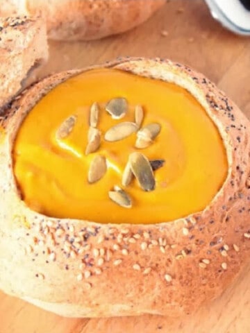 A Cuban Bread Bowl filled with creamy soup and pepita seeds.