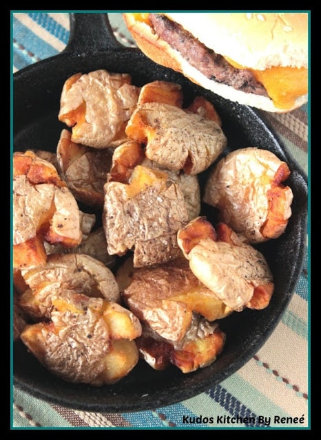 A bunch of crispy golden Fried Smashed Potatoes in a cast iron skillet.