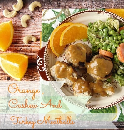 Overhead picture of turkey meatballs on a plate with orange slices and peas.