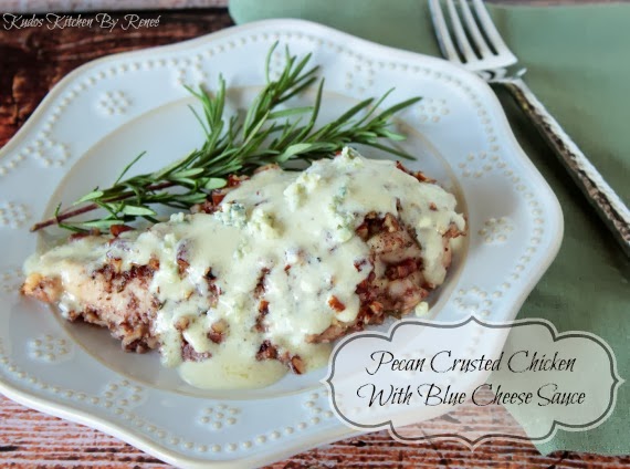 A breast of Pecan Chicken with Blue Cheese Sauce on a white plate with a sprig of rosemary.