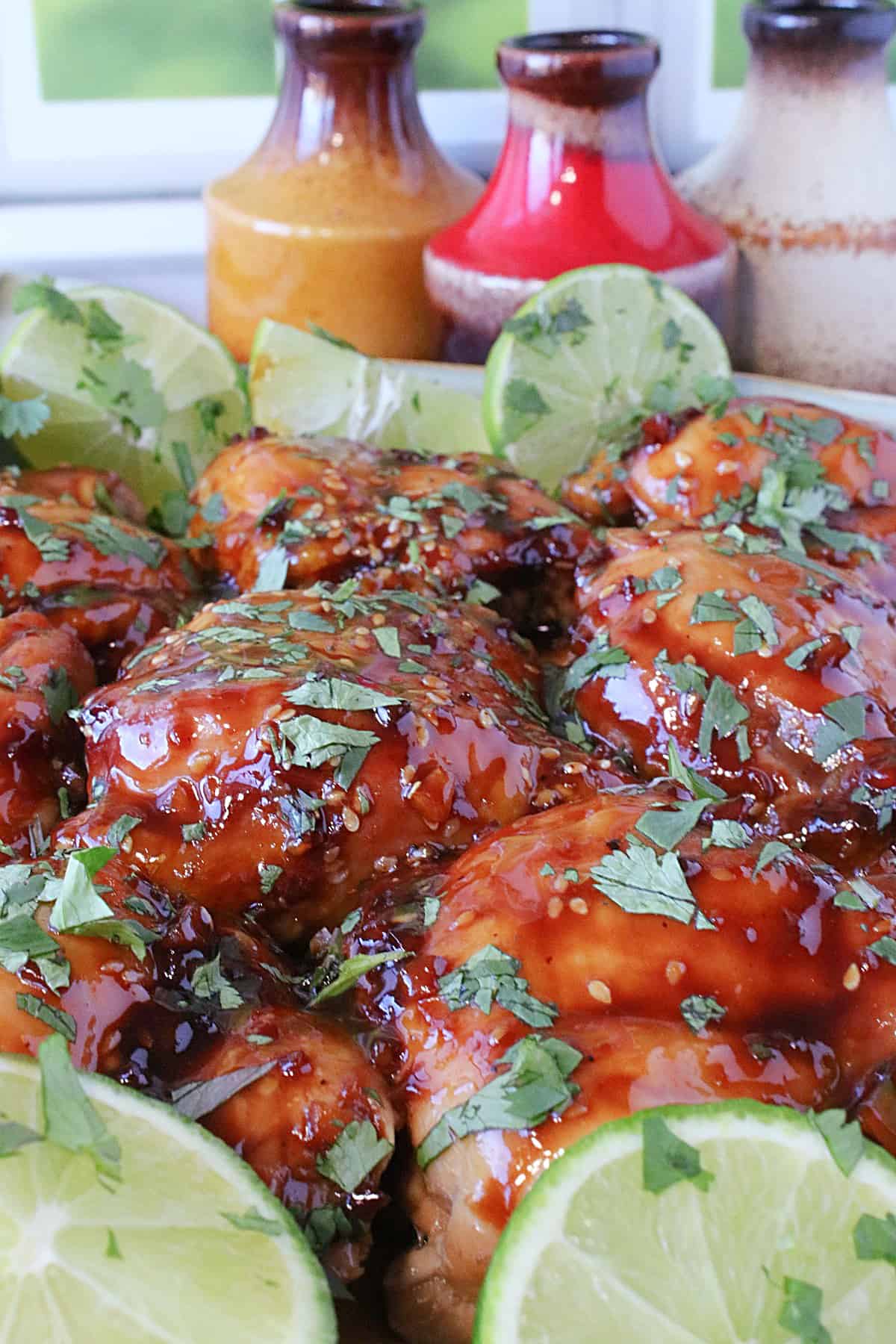 Deeply colored Teriyaki Glazed Chicken Thighs with limes and cilantro.