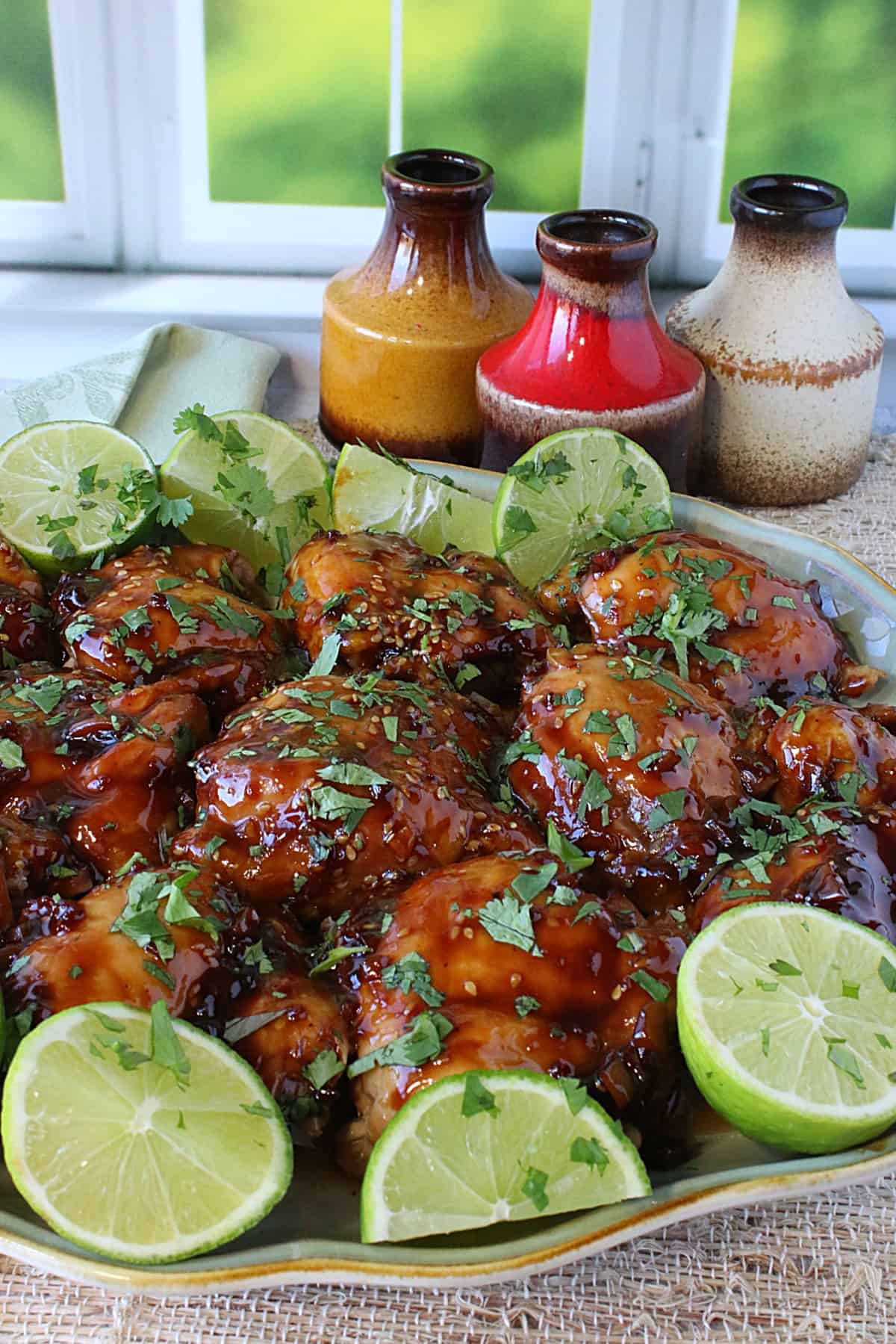 A platter filled with Teriyaki Glazed Chicken Thighs by a kitchen window.