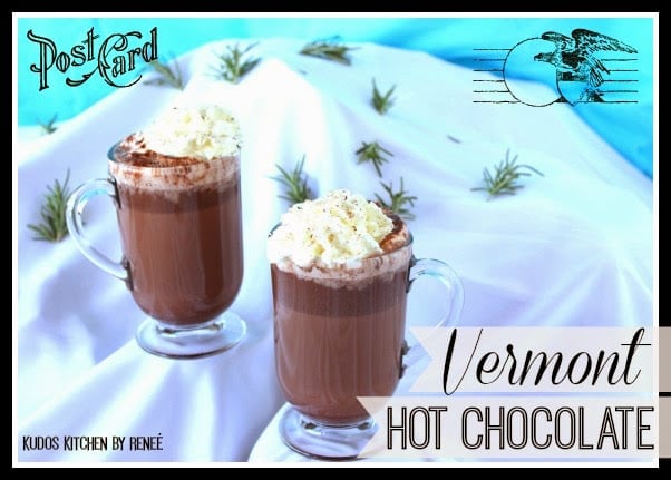 Postcard like image of two mugs of Vermont hot chocolate on a snow covered hill. 