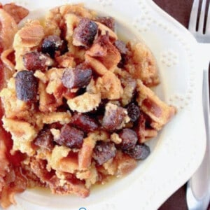 A large serving of Waffle and Sausage Bread Pudding on a white plate with a fork.