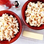An overhead photo of two bowls filled with Buffalo Popcorn and a butter dish with butter.