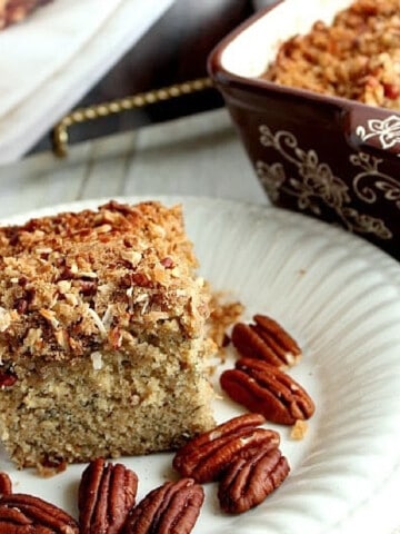 A square of Banana Pecan Breakfast Cake on a white plate with pecans surrounding it.