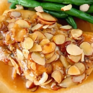 A closeup photo of a Chicken Beer Bake breast covered with sliced almonds.