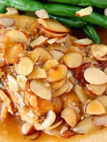 A closeup photo of a Chicken Beer Bake breast covered with sliced almonds.