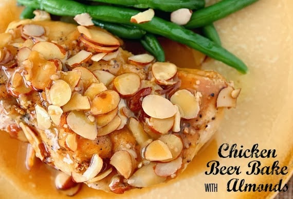 A horizontal photo of chicken beer bake covered with sauce and almonds along with green beans on a plate.