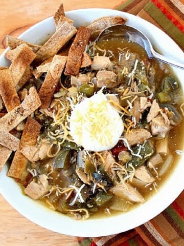 An overhead photo of a bowl of Chicken Fajita Soup with tortilla strips and a dollop of sour cream.