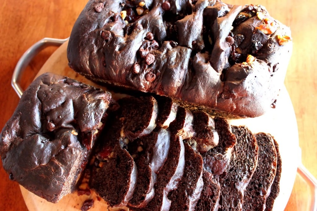 Overhead photo of a slice chocolate cherry yeast bread on a wooden cutting board