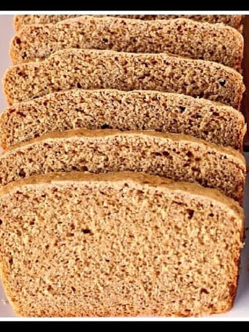 Slices of Oatmeal Molasses Bread on a plate with a serrated knife.
