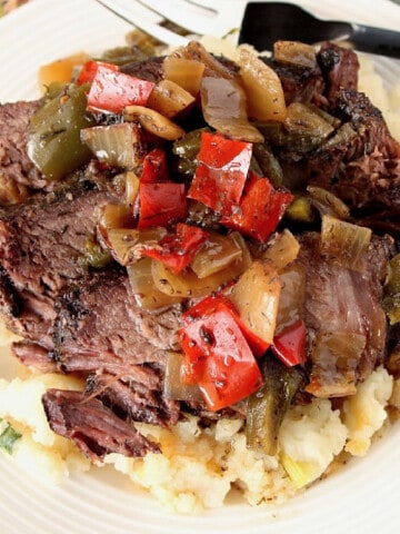 Slow Cooker Beef with Peppers, Onions and Dill over mashed potatoes on a plate.