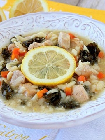 A serving of Chicken Lemon Orzo Soup in a bowl with a slice of lemon on top.
