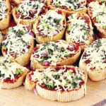 A bunch of Mini French Bread Pizza Appetizers topped with cheese and basil leaves.