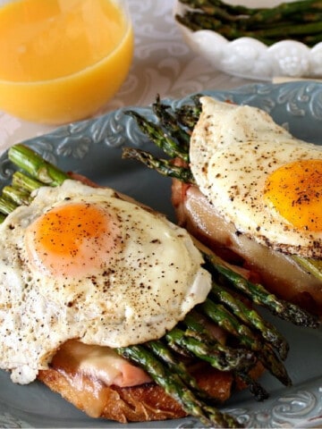 A Croque Madame Breakfast Sandwich with asparagus and fried eggs on top.
