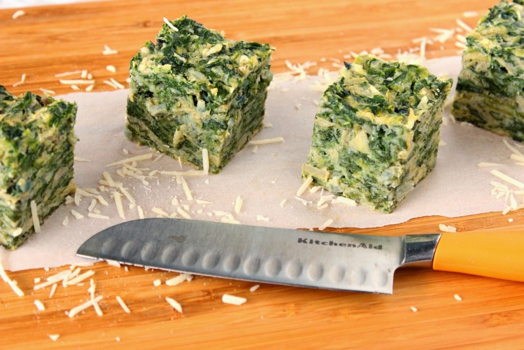 4 square of spinach artichoke appetizers on a cutting board with a knife