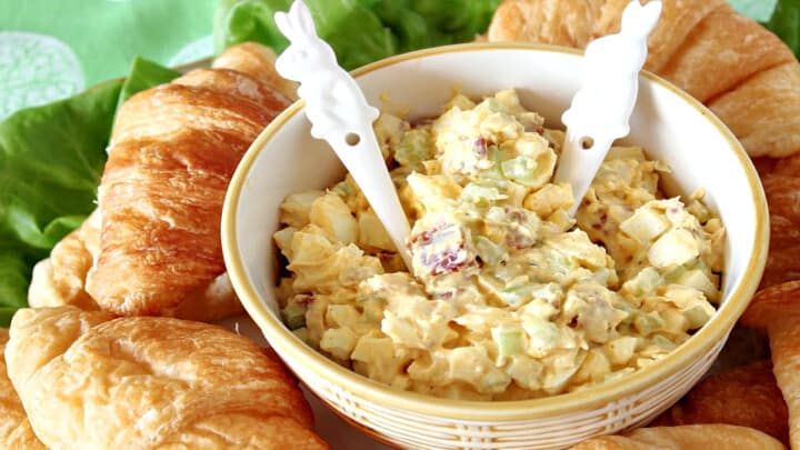 A bowl of Bacon Egg Salad with two bunny spoons surrounded by croissants.