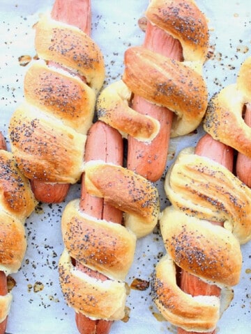Challah Hot Dogs with poppy seeds on a baking sheet.