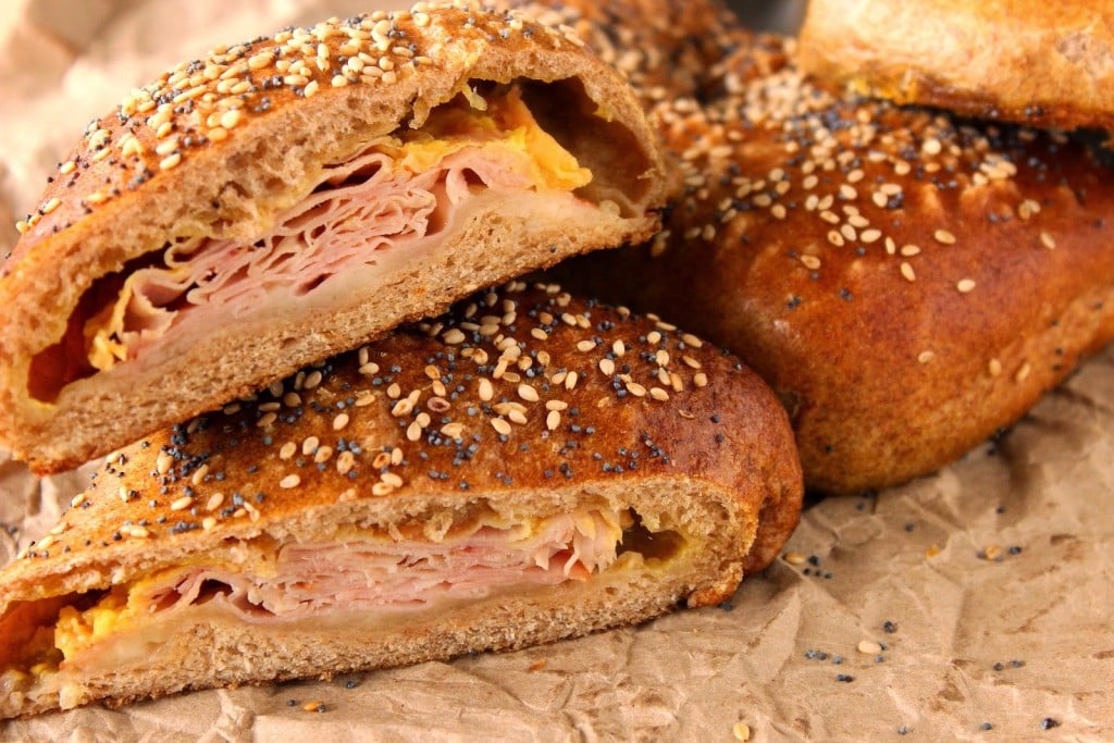 A stuffed Pretzel Pocket with ham and cheese on the inside and sesame and poppy seeds on the outside.