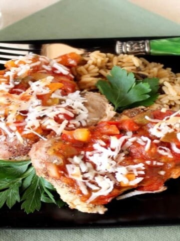 Tropical salsa chicken on a black square plate with a green fork and cilantro