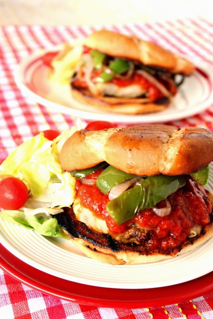 An Italian Sausage Pizza Burger with a toasted bun on a white plate.