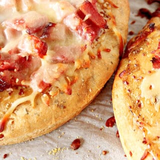 A horizontal closeup photo of two Leek and Onion Focaccia with ham and cheese.