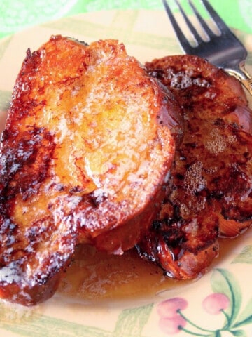 Two slices of Challah French Toast on a plate with a fork.