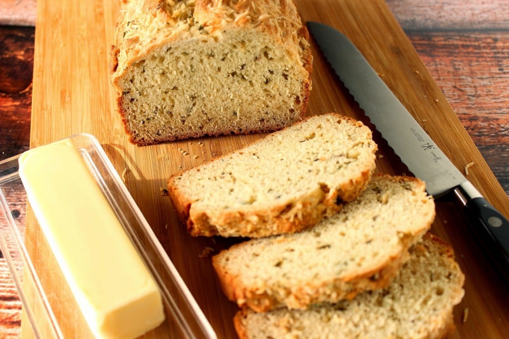 Slices of Homemade Soda bread with herbs and a stick of butter.