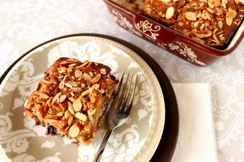 A golden brown slice of Berry Almond Oatmeal Coffee on a plate with a fork and napkin.