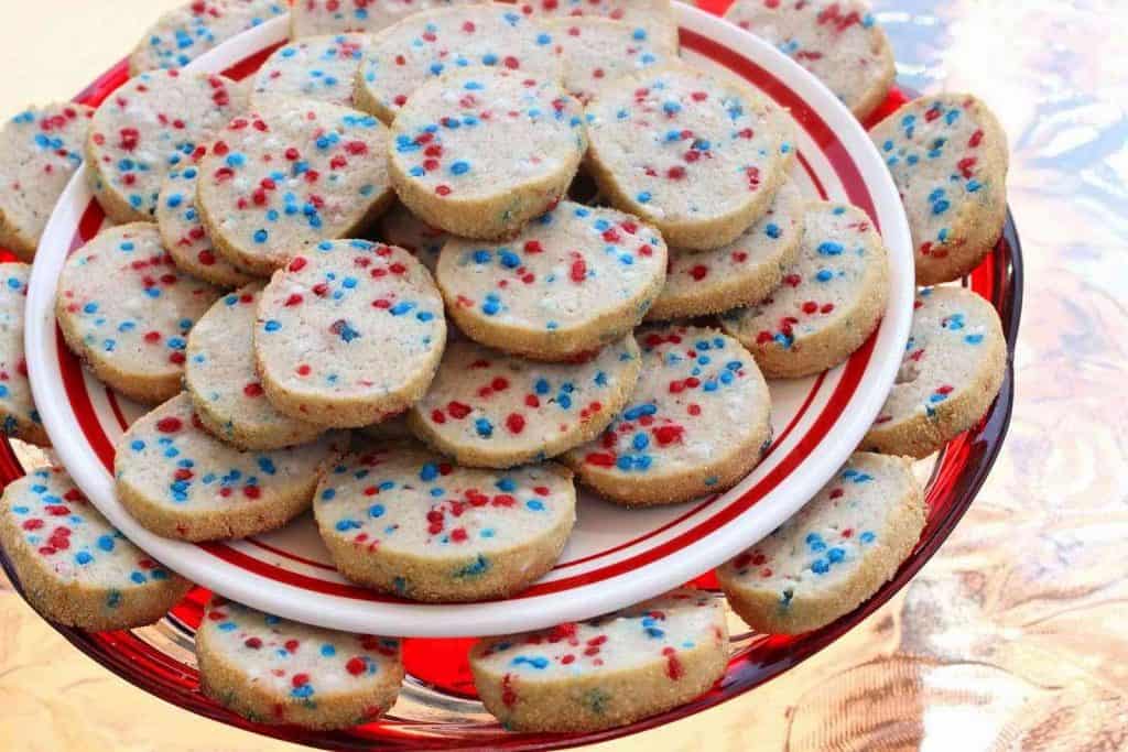 A tiered plate filled with cream cheese cookies with patriotic sprinkles.