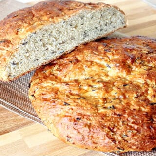 Two rustic loaves of Wild Rice Bread with Onions on a wooden board with a napkin.