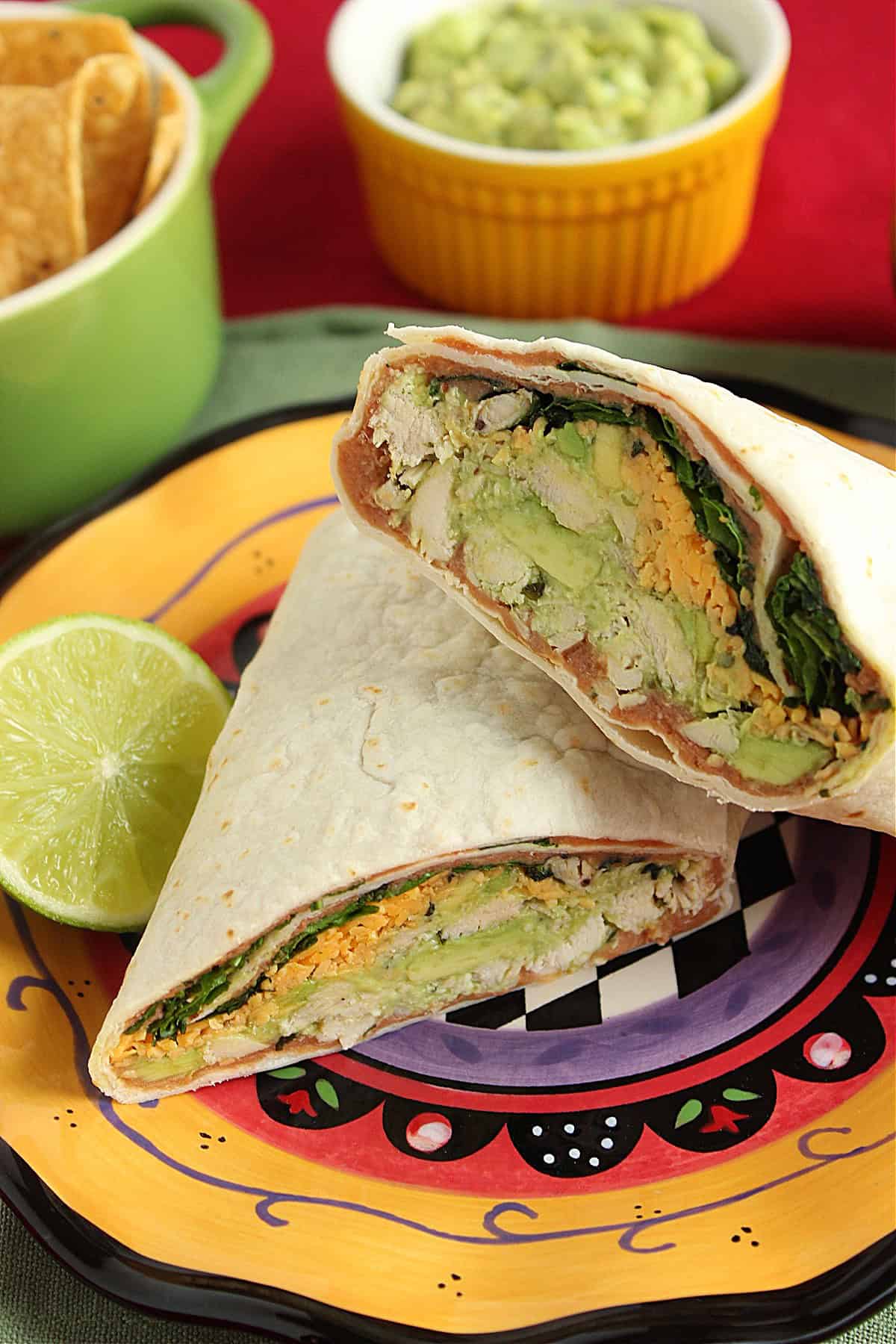 A colorful chicken and avocado wrap on a yellow plate.
